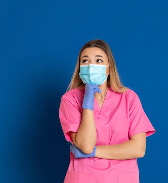 Jovem Médico Vestindo Rosto Máscara Uniforme Rosa Fundo Azul — Fotografia de Stock