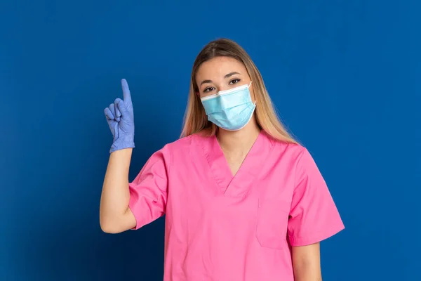 Jovem Médico Vestindo Rosto Máscara Uniforme Rosa Fundo Azul — Fotografia de Stock