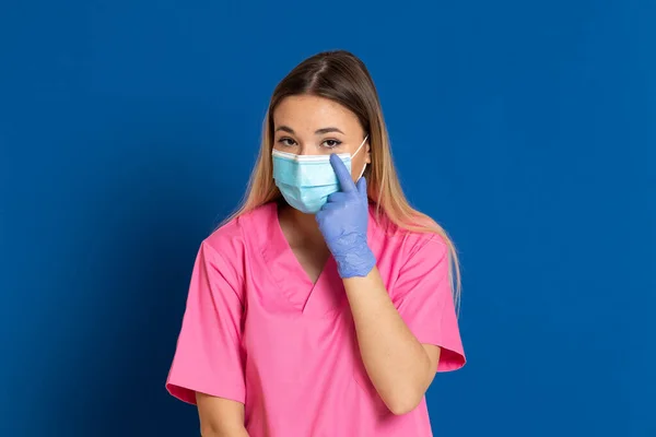 Jovem Médico Vestindo Rosto Máscara Uniforme Rosa Fundo Azul — Fotografia de Stock