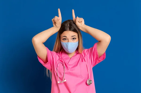 Jovem Médico Vestindo Rosto Máscara Uniforme Rosa Fundo Azul — Fotografia de Stock