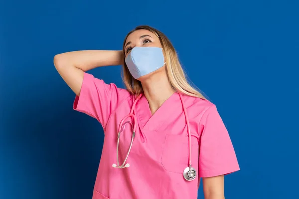 Jovem Médico Vestindo Rosto Máscara Uniforme Rosa Fundo Azul — Fotografia de Stock