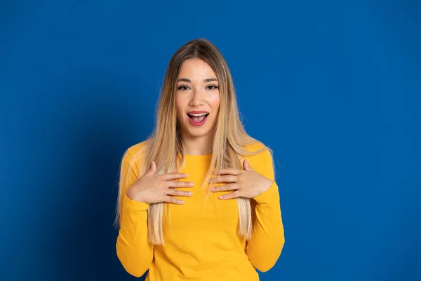 Blonde girl wearing a yellow T-shirt on a blue background