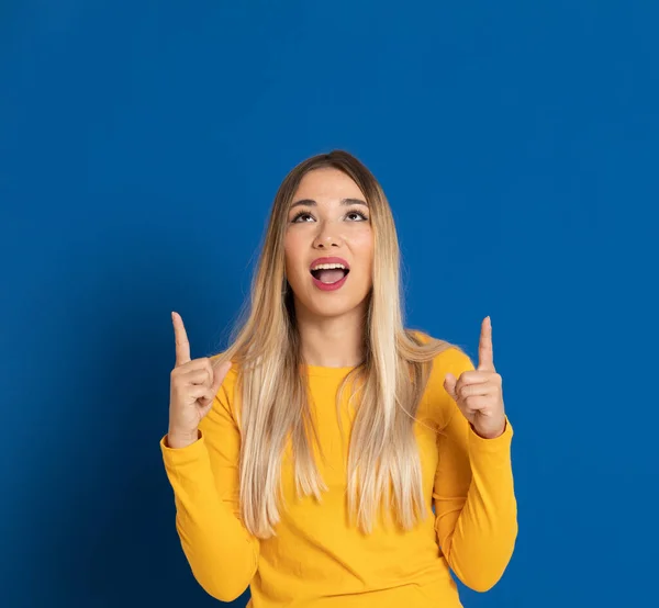 Blonde girl wearing a yellow T-shirt on a blue background