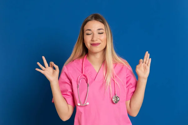 ブロンド医師とともにピンクの制服上の青の背景 — ストック写真