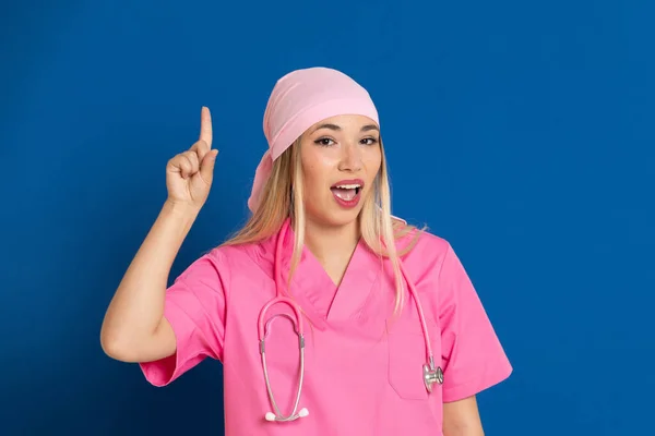 ピンクの制服を着た若い医師と青い背景のスカーフ — ストック写真