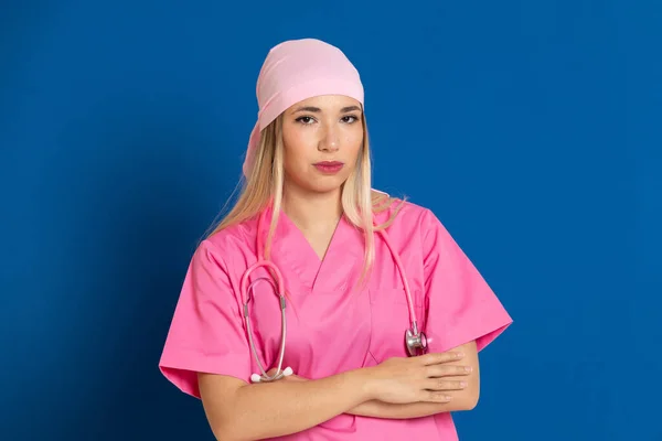 ピンクの制服を着た若い医師と青い背景のスカーフ — ストック写真