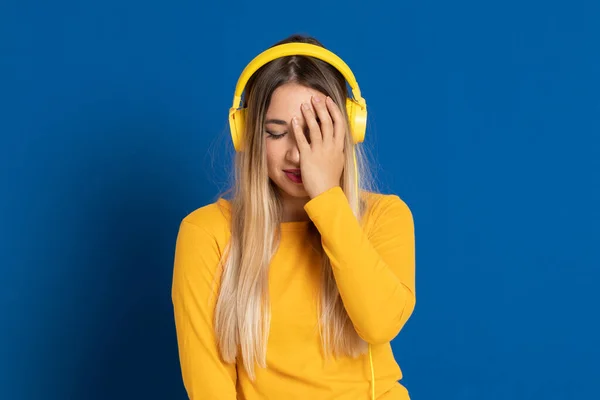 蓝色背景上的金发女孩的黄色耳机 — 图库照片