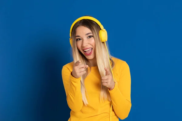 Blond Meisje Gele Hoofdtelefoon Een Blauwe Achtergrond — Stockfoto