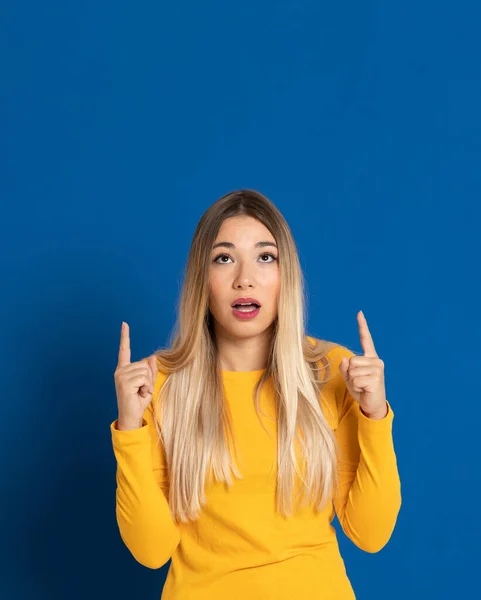 Blonde girl wearing a yellow T-shirt on a blue background