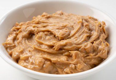 Beyaz arka plana yerleştirilmiş fıstık ezmesi yakın plan.