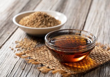 Susam yağı ve susam tohumları eski bir ahşap arka plana yerleştirilir.