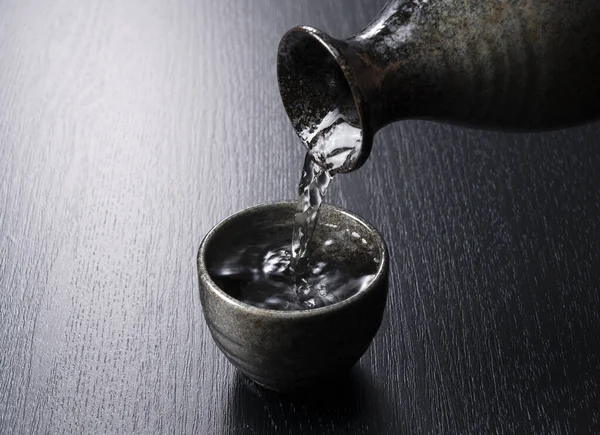 Sake Gieten Een Sake Cup Een Zwarte Achtergrond — Stockfoto