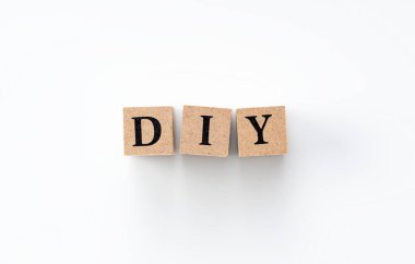 Beyaz zemin üzerinde DIY harfleri olan tahta bir blok.