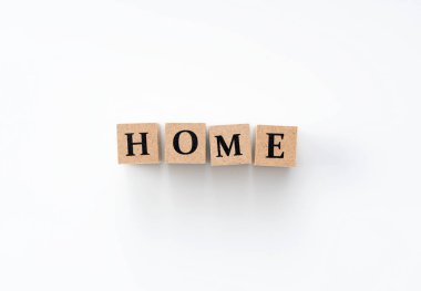 Üzerinde beyaz bir arkaplan üzerinde ev kelimesi yazan tahta bir blok..