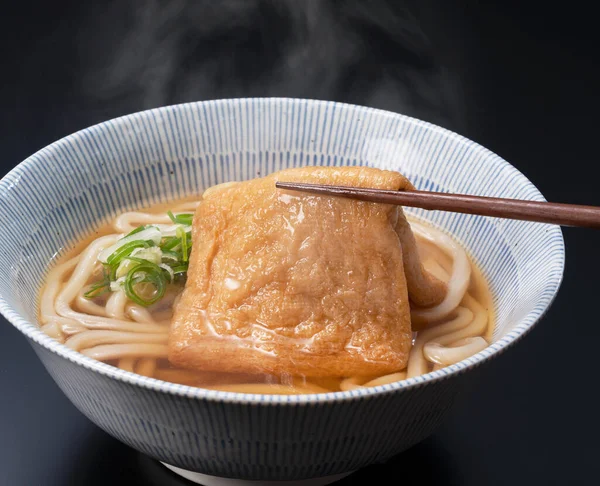 Udon noodles in a hot soup with deep fried tofu