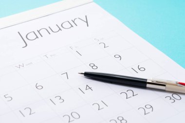 Mavi arkaplanda bir takvim ve kalemin yakın plan görüntüsü