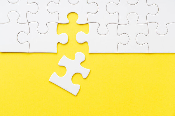 Yellow background and white jigsaw puzzle viewed from above