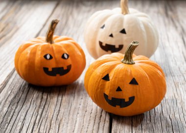 Eski ahşap arka planda turuncu ve beyaz balkabağı fenerleri.