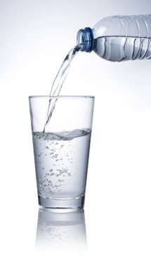 Beyaz arka plana yerleştirilmiş temiz bir bardağa şişe suyu dök..