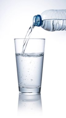 Beyaz arka plana yerleştirilmiş temiz bir bardağa şişe suyu dök..