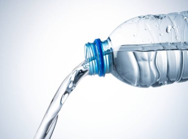 Beyaz zemin üzerinde plastik bir şişeden suyla kapanıyor.