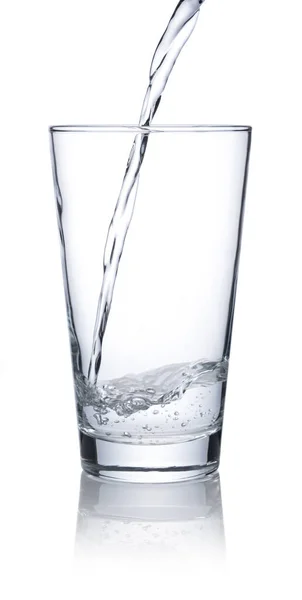 白い背景に置かれた透明なガラスに水を注ぐ — ストック写真