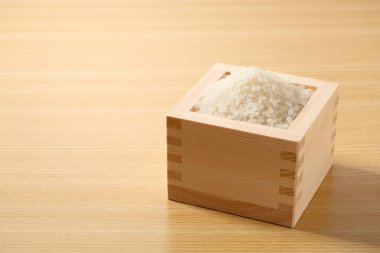 A closeup of rice in a Japanese measure cup in a wooden background clipart