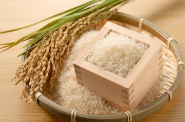 Rice in a Japanese Masu box and rice in a colander on a wooden background clipart