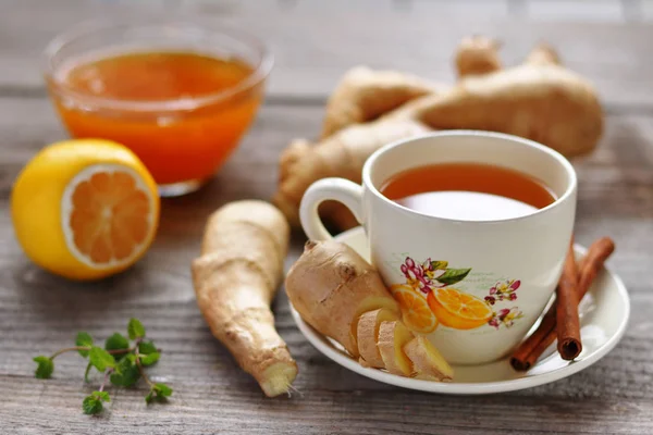 A cup of ginger tea, ginger roots, lemon and honey