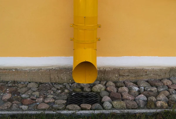yellow downpipe against the yellow wall of the old building