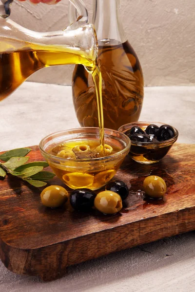 Bottle virgin olive oil and oil in a bowl with some olives.