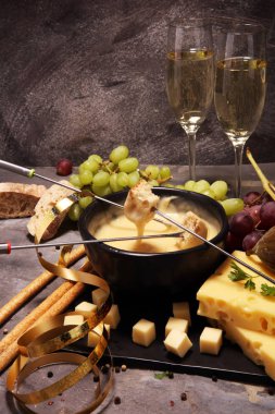 Bir kış akşamında gurme İsviçre fondü yemek peynir fondü iki çatal ekmek daldırma ile ısıtmalı bir sürahi yanında bir gemide çeşitli peynir ile