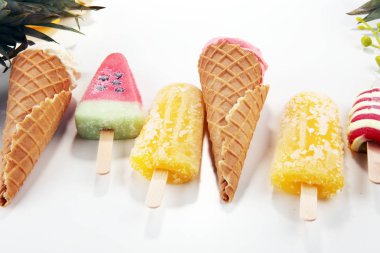 Yoğurt veya yumuşak kıvamlı dondurma waffle koni ve tropikal meyve ile renkli buzlu çubuk vanilya dondurulmuş