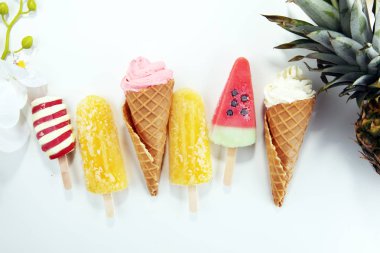 Yoğurt veya yumuşak kıvamlı dondurma waffle koni ve tropikal meyve ile renkli buzlu çubuk vanilya dondurulmuş