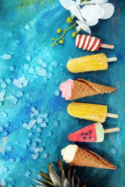 Yoğurt veya yumuşak kıvamlı dondurma waffle koni ve tropikal meyve ile renkli buzlu çubuk vanilya dondurulmuş