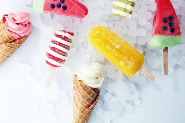 Vanilla frozen yogurt or soft ice cream in waffle cone and Colorful popsicle
