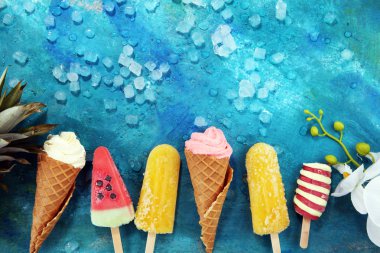 Yoğurt veya yumuşak kıvamlı dondurma waffle koni ve tropikal meyve ile renkli buzlu çubuk vanilya dondurulmuş