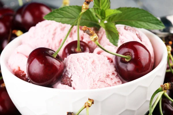 Homemade cherry ice cream and a bunch of cherries on table.