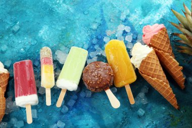 Yoğurt veya yumuşak kıvamlı dondurma waffle koni ve tropikal meyve ile renkli buzlu çubuk vanilya dondurulmuş