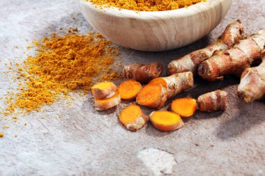 Zerdeçal tozu ve gri arka plan üzerinde taze zerdeçal.