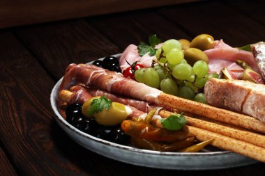 İtalyan antipasti şarap aperatifler küme. Peynir çeşitli, Akdeniz zeytin, turşu, Prosciutto di Parma, salam ve şarap gözlük siyah grunge arka plan üzerinde