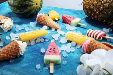 Yoğurt veya yumuşak kıvamlı dondurma waffle koni ve tropikal meyve ile renkli buzlu çubuk vanilya dondurulmuş