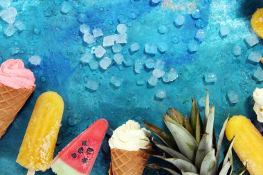 Yoğurt veya yumuşak kıvamlı dondurma waffle koni ve tropikal meyve ile renkli buzlu çubuk vanilya dondurulmuş