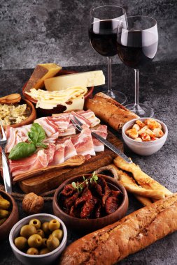 İtalyan antipasti şarap aperatifler küme. Peynir çeşitli, Akdeniz zeytin, turşu, Prosciutto di Parma, domates, enginar ve şarap gözlük. İspanyolca tapas