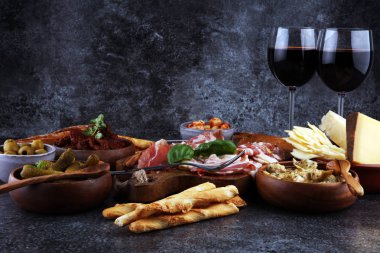 İtalyan antipasti şarap aperatifler küme. Peynir çeşitli, Akdeniz zeytin, turşu, Prosciutto di Parma, domates, enginar ve şarap gözlük. İspanyolca tapas