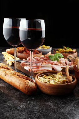İtalyan antipasti şarap aperatifler küme. Peynir çeşitli, Akdeniz zeytin, turşu, Prosciutto di Parma, domates, enginar ve şarap gözlük. İspanyolca tapas