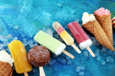 Yoğurt veya yumuşak kıvamlı dondurma waffle koni ve tropikal meyve ile renkli buzlu çubuk vanilya dondurulmuş