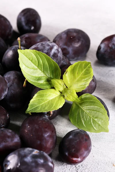 Erik beyaz taş zemin üzerine. Mavi erik meyve yarısı. Yaprakları ile birçok güzel Erik