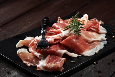 Italian prosciutto crudo or jamon with rosemary. Raw ham. clipart