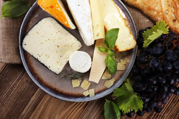 Rustik plaka üzerinde farklı peynir peynir tabağı.